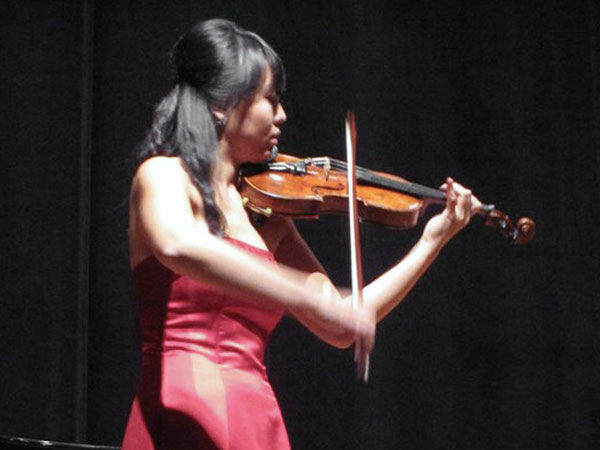 Yoonjoo playing violin in a red gown